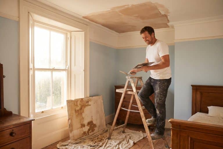 Plasterer skimming a repaired section of ceiling after a water leak